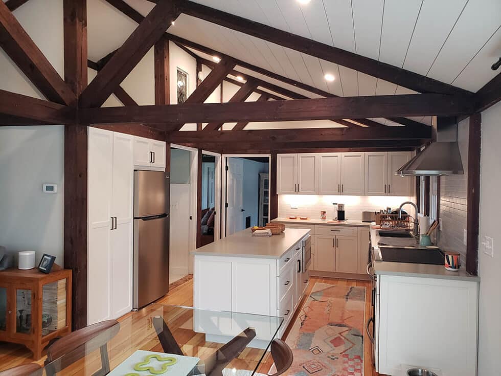 Modern kitchen renovation featuring white cabinetry, stainless steel appliances, and exposed wooden beams, showcasing Ace Home Medics' design expertise in North Reading, MA.
